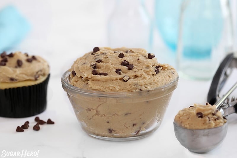 Cookie Dough Frosting in a glass bowl with a cupcake scoop next to it.