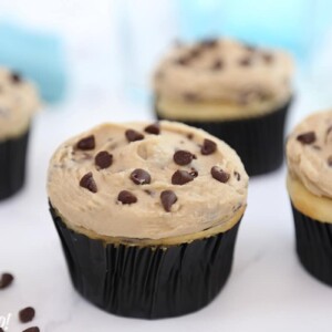 Four cupcakes frosted with Cookie Dough Frosting on a white surface.