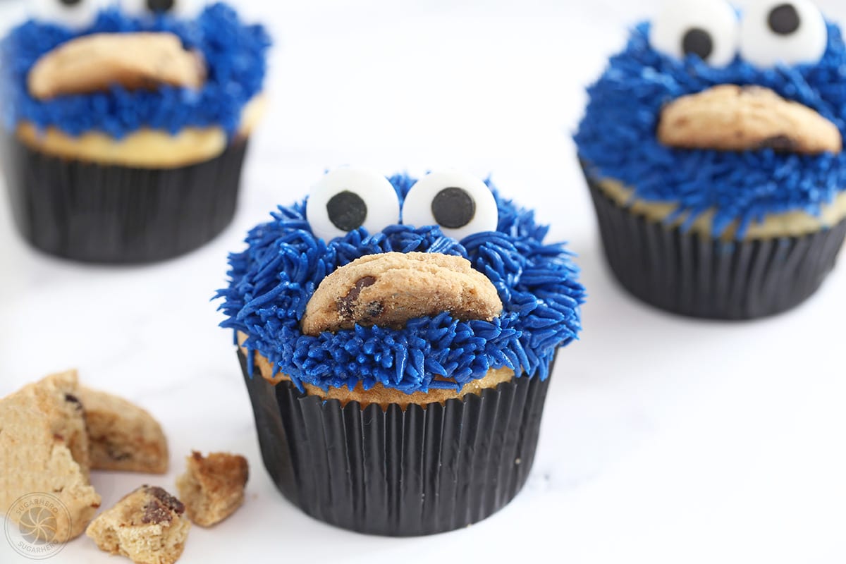 Three Cookie Monster Cupcakes on a white surface.