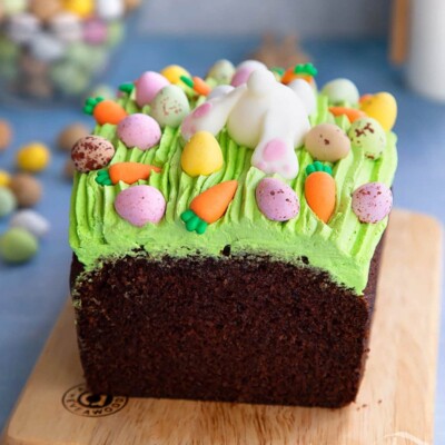 Chocolate loaf cake with green buttercream grass and Easter egg candies on top.
