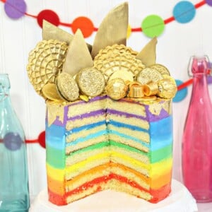 Gold-Topped Rainbow Cake sliced open, revealing the multi-colored rainbow frosting layers inside.