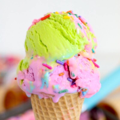 Ice cream cone with two scoops of brightly colored rainbow ice cream on top.
