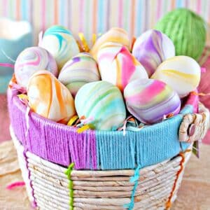 Colorful pastel truffles shaped like eggs in a woven Easter basket.