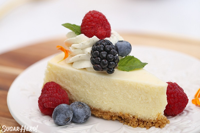 Slice of cheesecake with whipped cream and fresh berries on top.