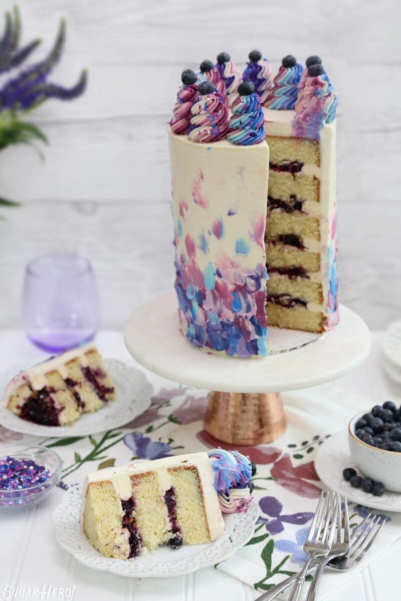 Tall Blueberry Layer Cake with slices taken out of it, and two slices sitting in front.