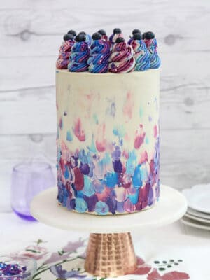 Blueberry Layer Cake with blue and purple frosting on a gold-bottomed cake stand.