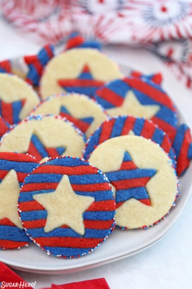 Red, white, and blue striped star cookies on a white plate.