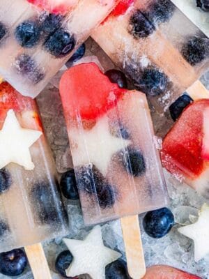Homemade Fruit Popsicles on a bed of ice with a bite taken out of the center popsicle.