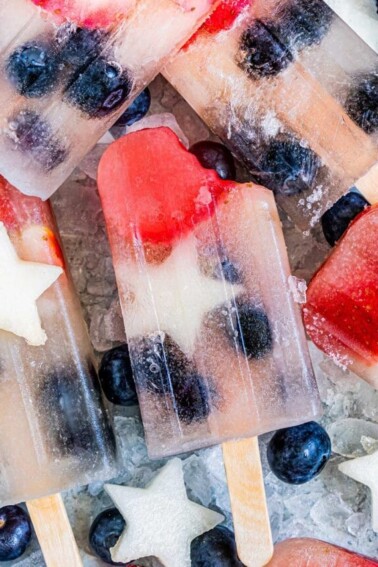 Homemade Fruit Popsicles on a bed of ice with a bite taken out of the center popsicle.