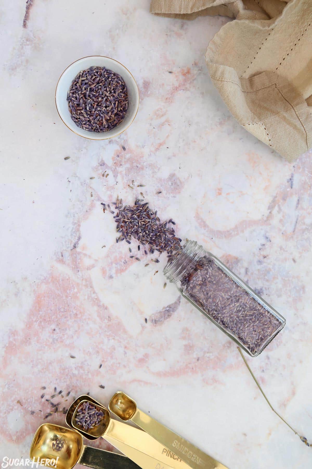 Overhead shot of dried culinary lavender in a small bowl and spilling out of a glass spice jar.