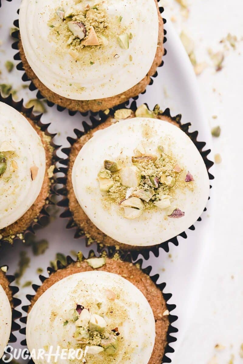 Overhead shot of zucchini cupcakes with lime cream cheese frosting and chopped pistachios.