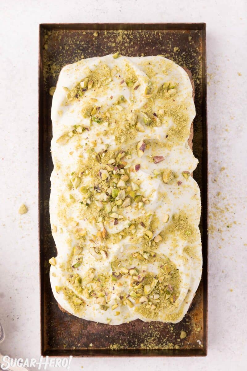 Overhead shot of zucchini bread frosted with cream cheese frosting, with crushed pistachios sprinkled on top.