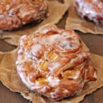 3 Apple Cider Fritters cooling on brown paper.