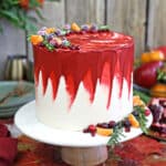 Brown Sugar Cranberry Cake on a white cake platter with fruit in the background.