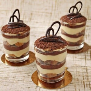 3 cups of chocolate tiramisu on golden coasters.