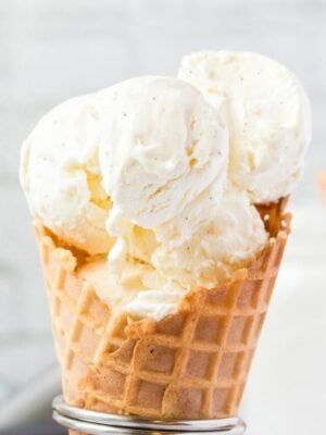 Close-up of waffle cone holding big scoops of vanilla bean ice cream.