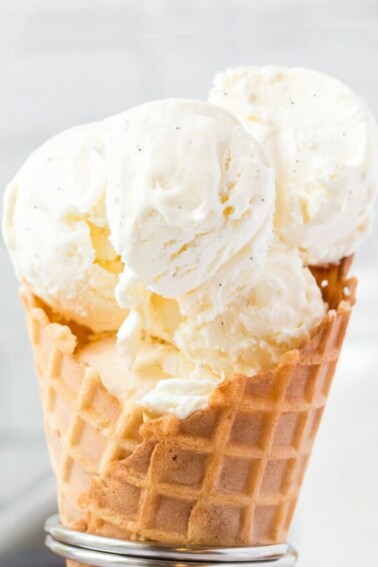 Close-up of waffle cone holding big scoops of vanilla bean ice cream.