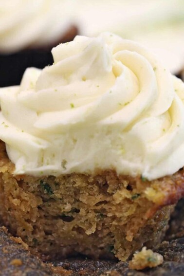 Lime Cream Cheese Frosting swirled on a zucchini cupcake with a bite removed to show texture.