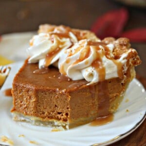 Slice of Dulce de Leche Pumpkin Pie on a white plate with bites removed to show texture and drizzled with dulce de leche.