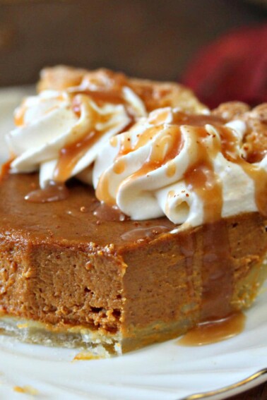 Slice of Dulce de Leche Pumpkin Pie on a white plate with bites removed to show texture and drizzled with dulce de leche.