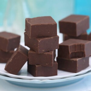 Several stacks of fudge on a white plate with a bite out of piece on the right.