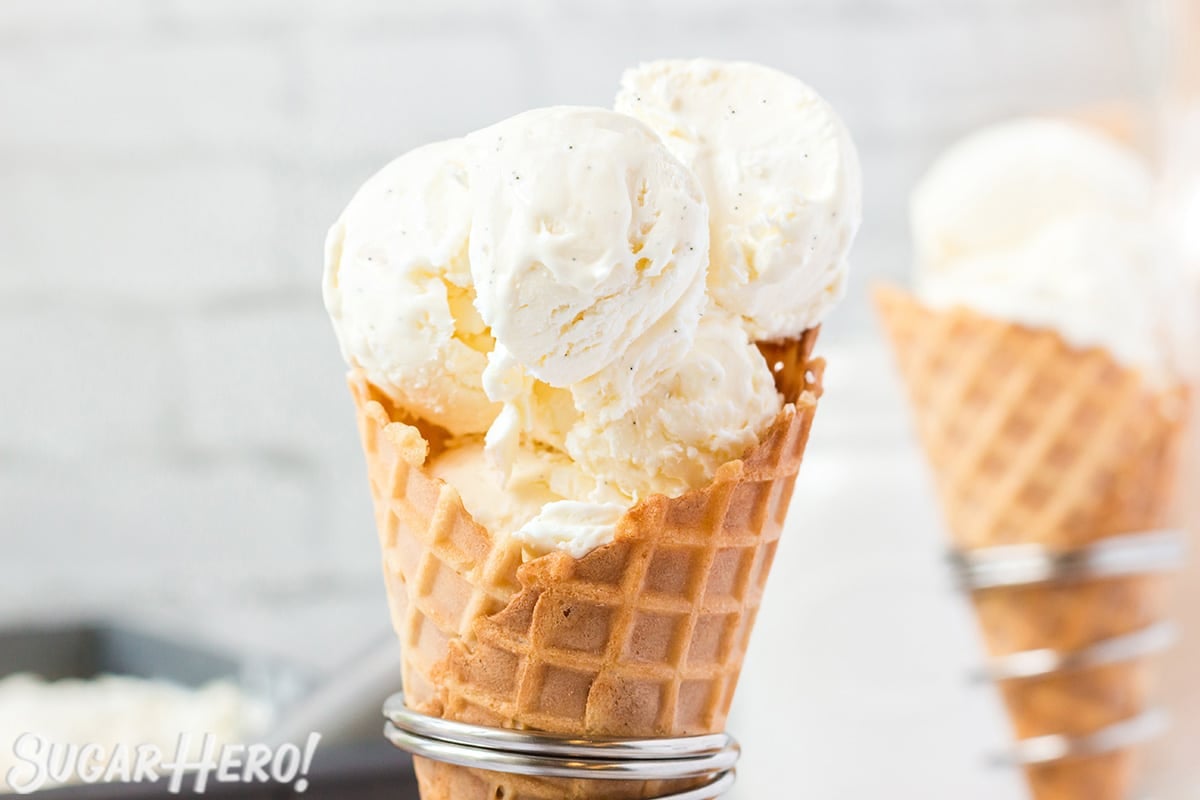 Close-up of waffle cone holding big scoops of vanilla bean ice cream.