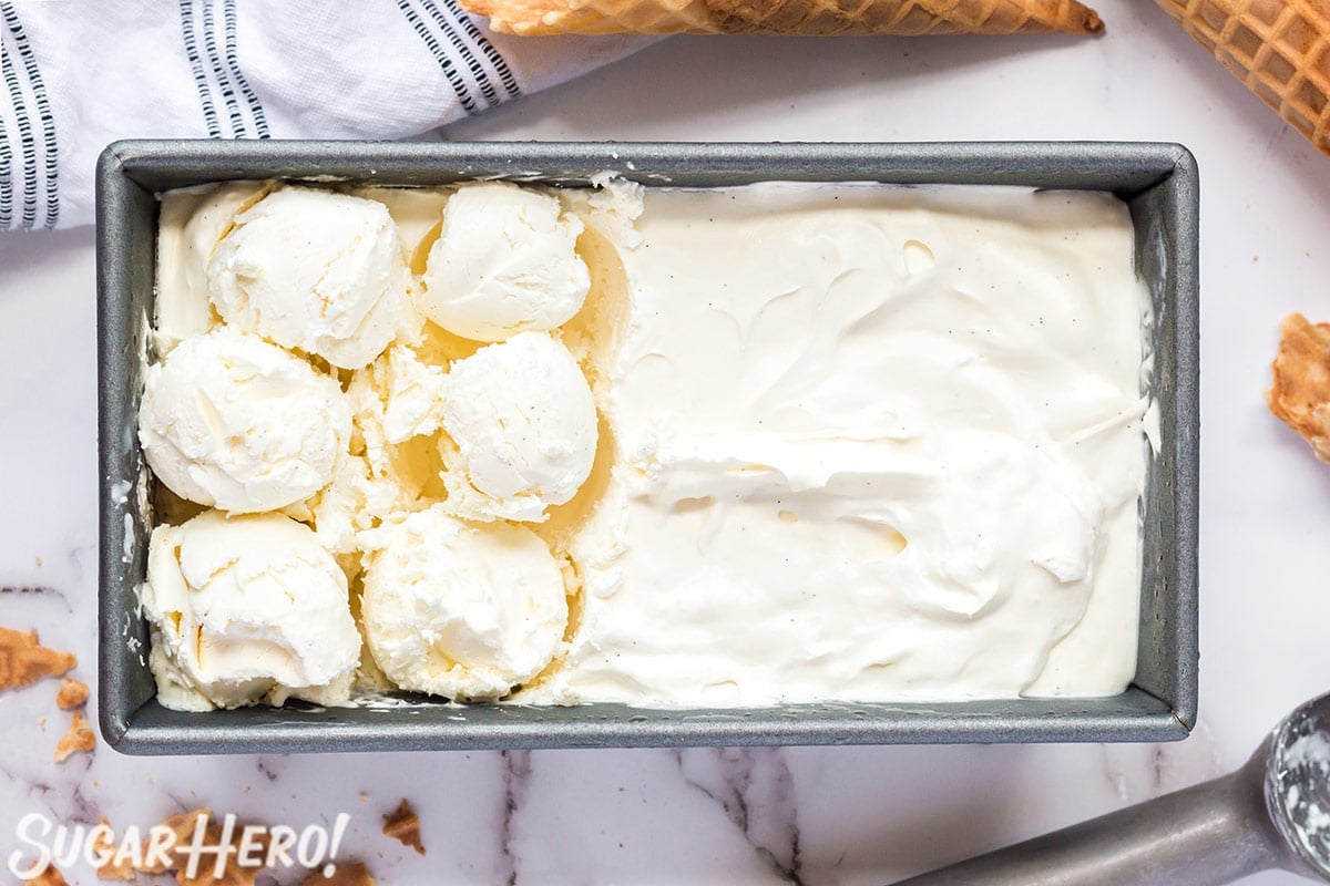 Overhead shot of vanilla ice cream in a loaf pan, with six scoops taken out.