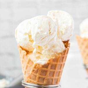 Close-up of waffle cone holding big scoops of vanilla bean ice cream.
