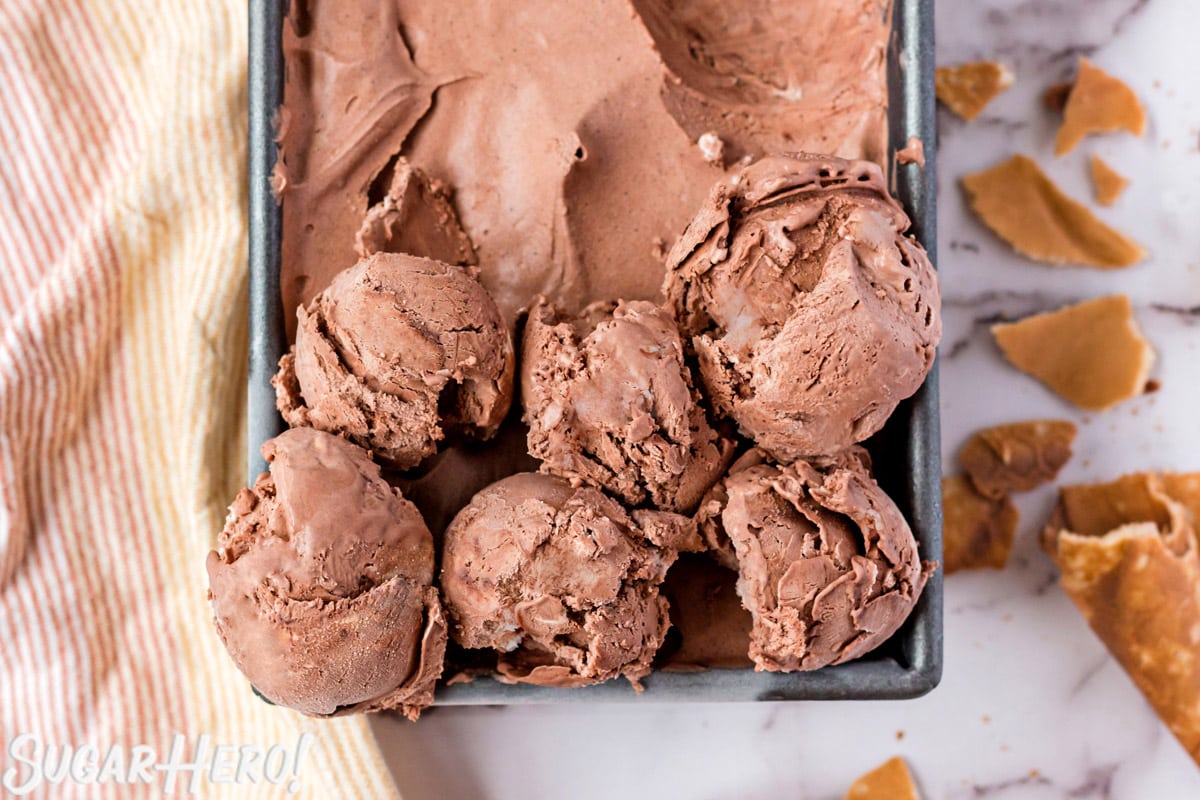 No-Churn Chocolate Ice Cream in a silver container with 6 scoops to show texture and a silver ice cream scoop inserted.