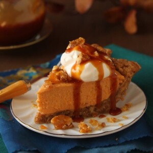 Slice of Oatmeal Walnut Butterscotch Pie with a dollop of whipped cream and caramel on top on a circular white plate.