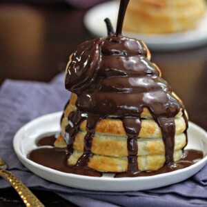 Puff Pastry-Wrapped Pear drizzled with chocolate espresso sauce on a white plate.