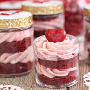 Close up of red velvet cake in a jar with the lid off and a heart on top.