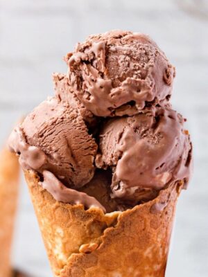 Close-up of three scoops of chocolate ice cream in a waffle cone.