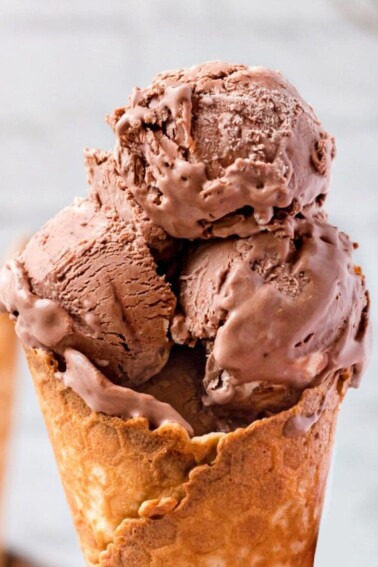 Close-up of three scoops of chocolate ice cream in a waffle cone.