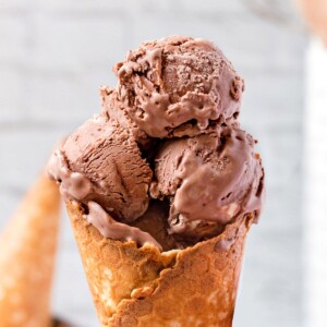 Close-up of three scoops of chocolate ice cream in a waffle cone.