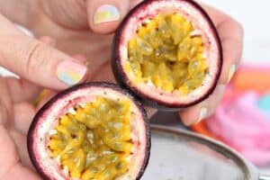 Photo of hands holding a cut passion fruit, with text overlay for Pinterest.