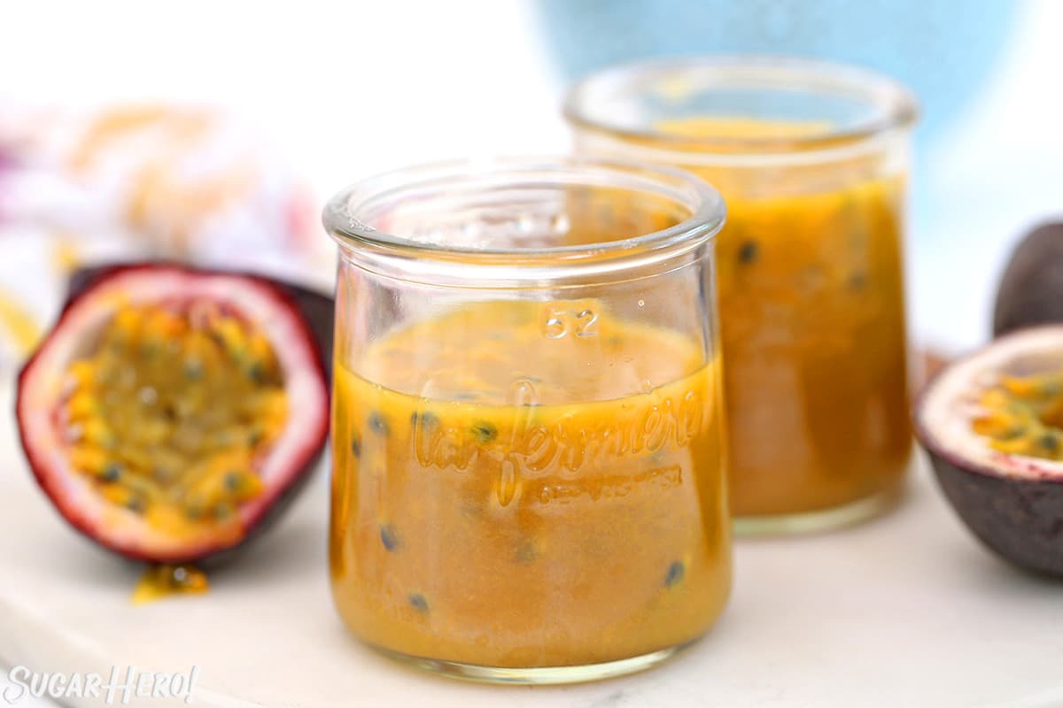 Passion Fruit Pulp in two small glass jars, with cut passion fruit around them.