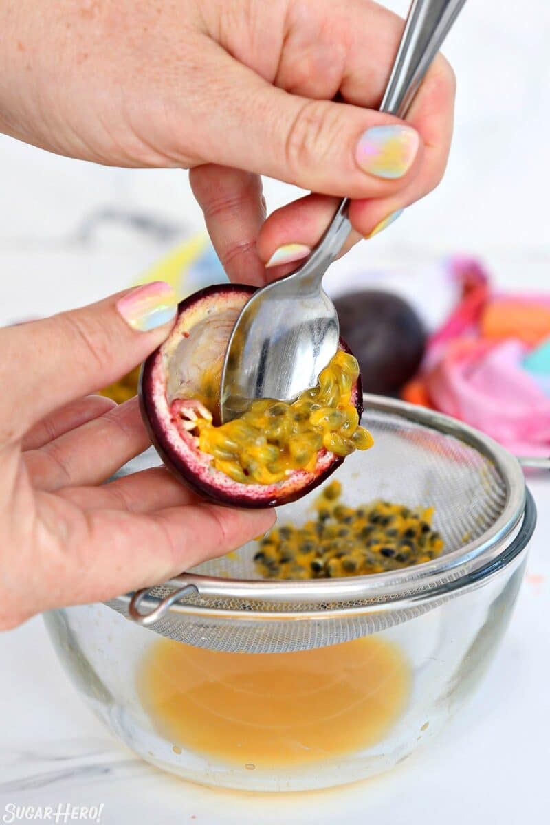 Scooping out the insides of a passion fruit into a wire mesh strainer.