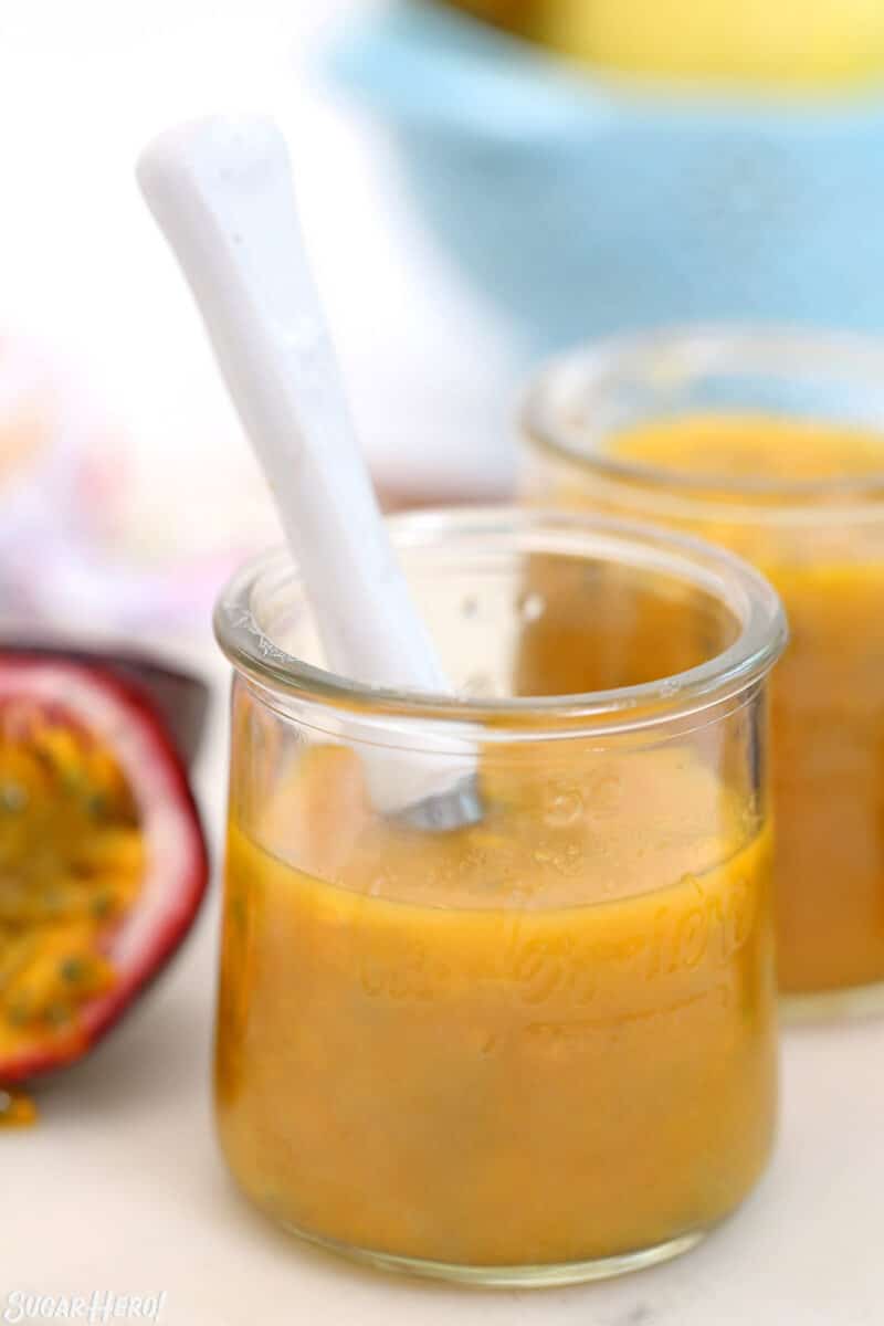 Passion fruit puree in a glass jar with a white spoon sticking out.