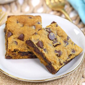 Two Pumpkin Chocolate Chip Bars on a gold rimmed white plate next to a golden fork.