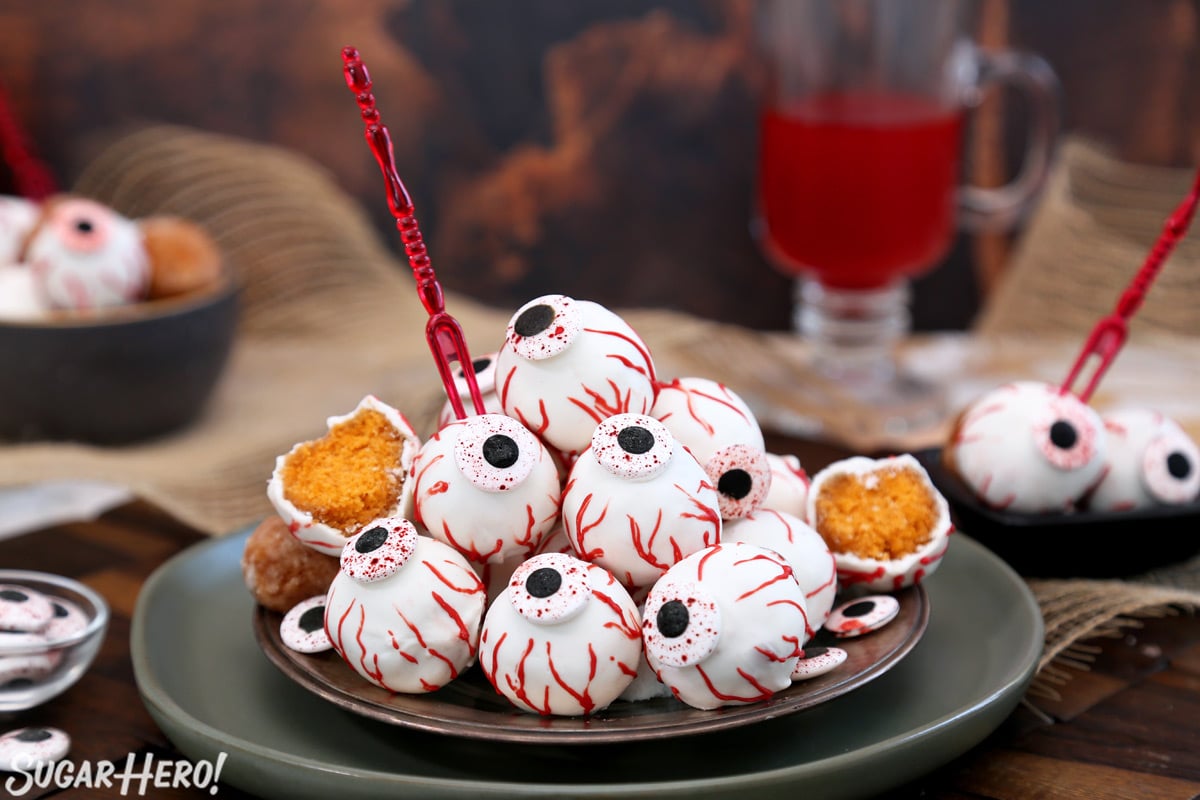 Plate of Donut Hole Eyeballs with red appetizer forks sticking out of some of them.