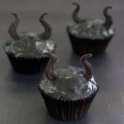 3 Maleficent Cupcakes on a grey surface.