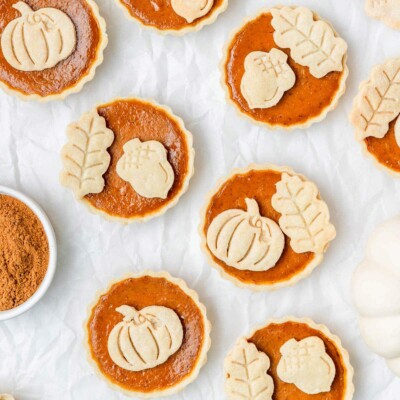 Overhead shot of mini pumpkin tarts decorated with pastry pumpkins and leaves.