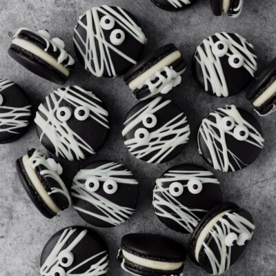 A pile of Black Cocoa Mummy Macarons on a marble surface.