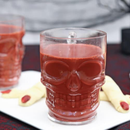 Red Velvet Hot Chocolate in a clear skull-shaped mug on a white serving platter.