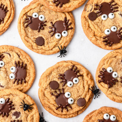 Close up of several Spider Pumpkin Chocolate Chip Cookies on parchment paper.