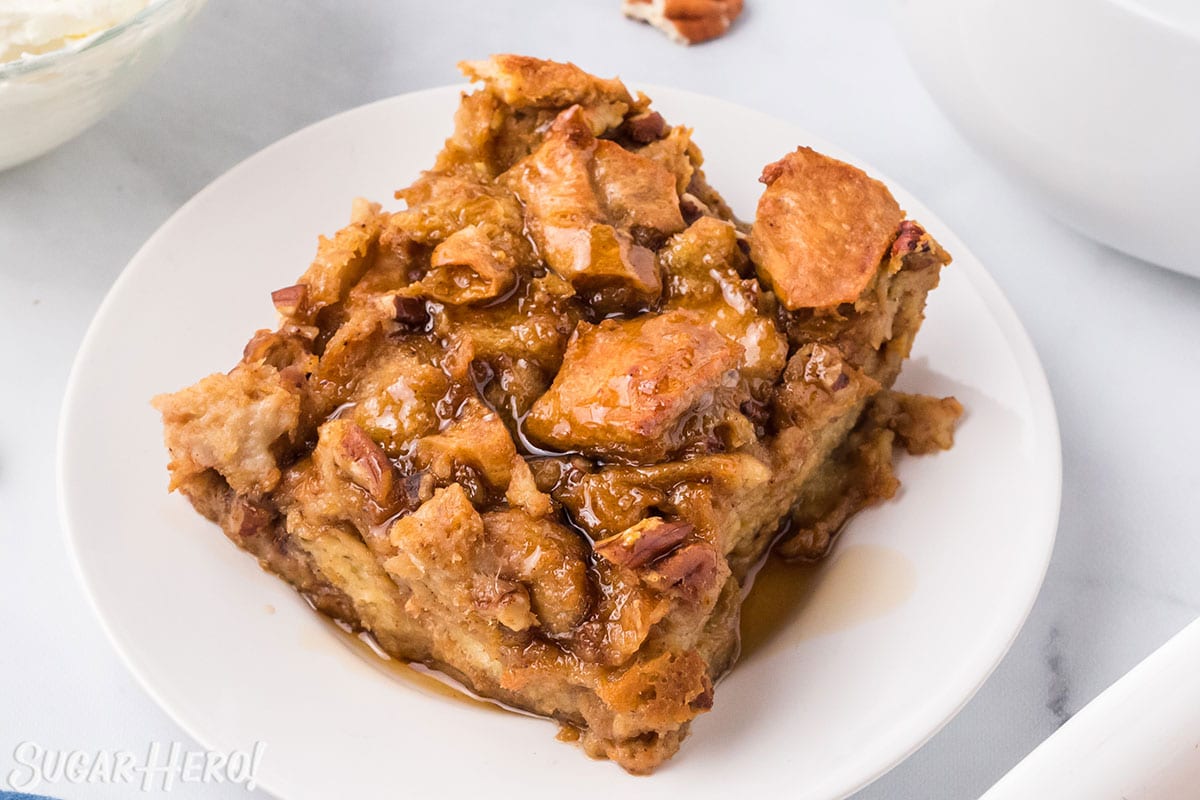 Slice of Pumpkin Bread Pudding on a white plate, drizzled with cinnamon syrup.