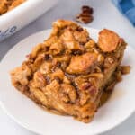 Slice of Pumpkin Bread Pudding drizzled with cinnamon syrup, on a white plate.