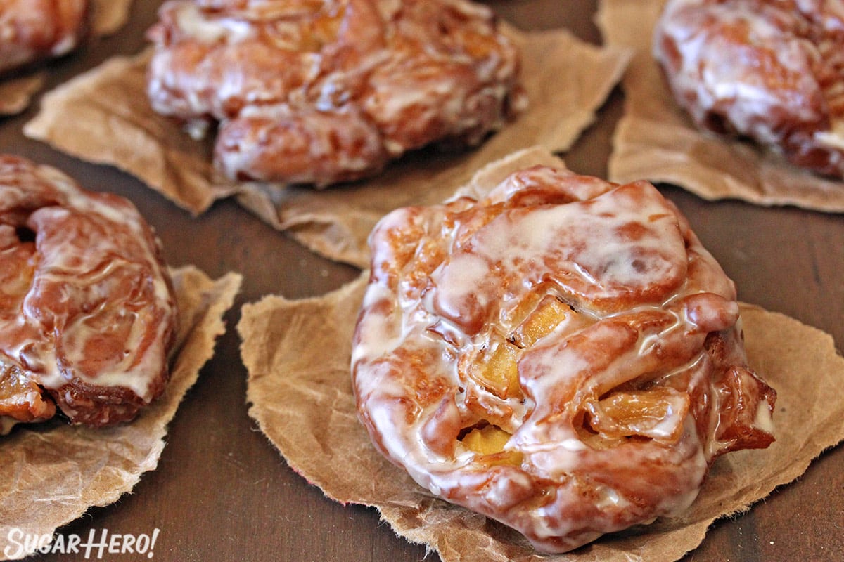 Close-up of Apple Cider Fritter on brown parchment paper on wooden surface.