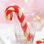 Candy Cane Cookies standing up in a clear glass with gold and silver dot accents.